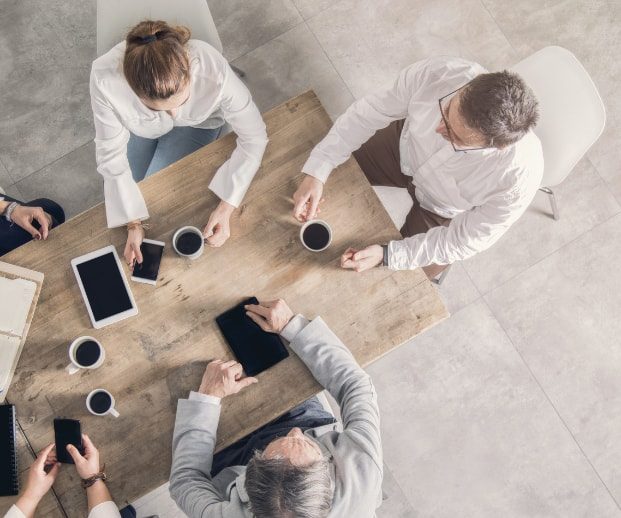 Machbarkeit Mieterstrom prüfen Menschen sitzen an einem Tisch mit Kaffee und digitalen Geräten.